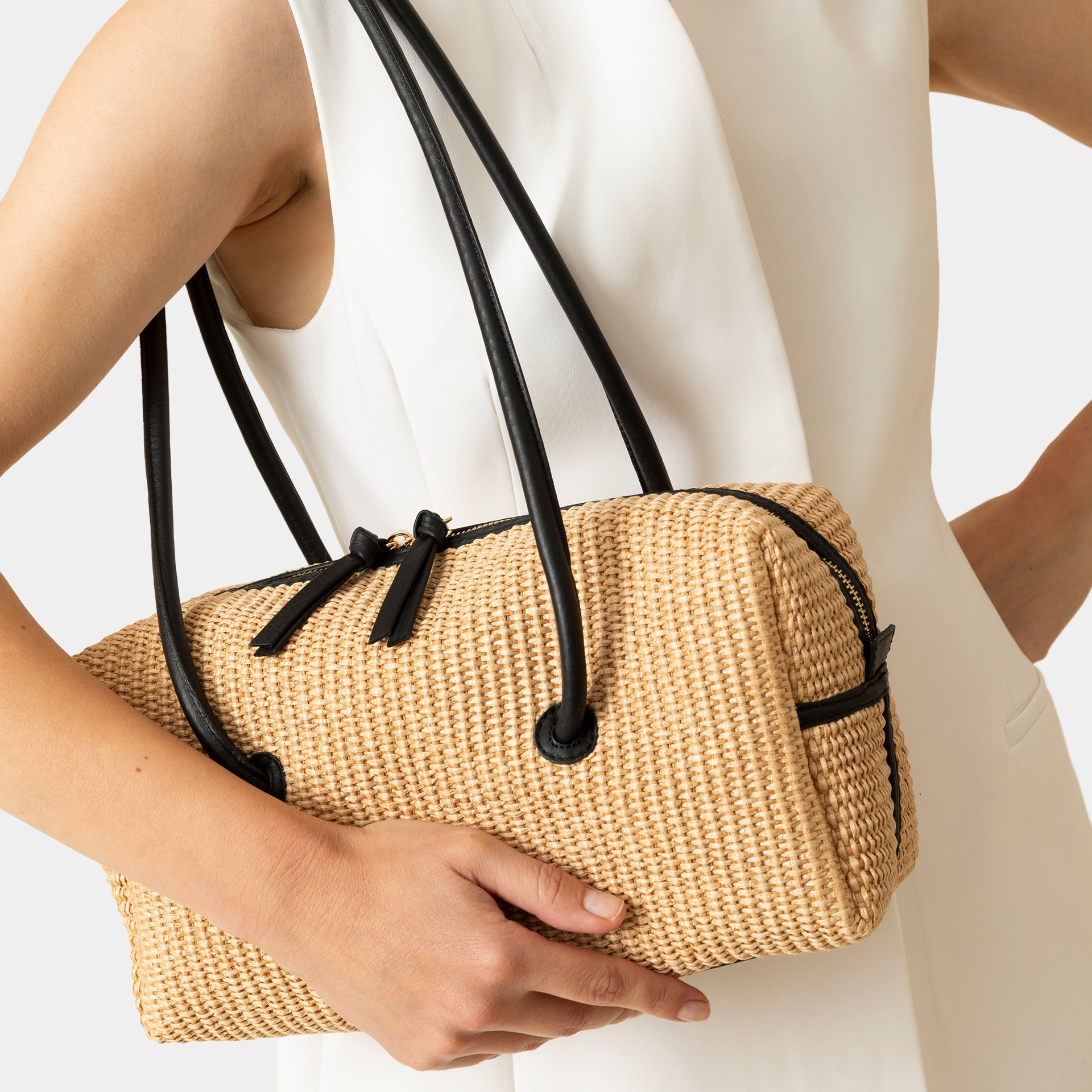 borsa Carol in rafia ecru e pelle nera del marchio Arron scultorea grafica e di design con manico rigido stile minimal giapponese indossata a spalla