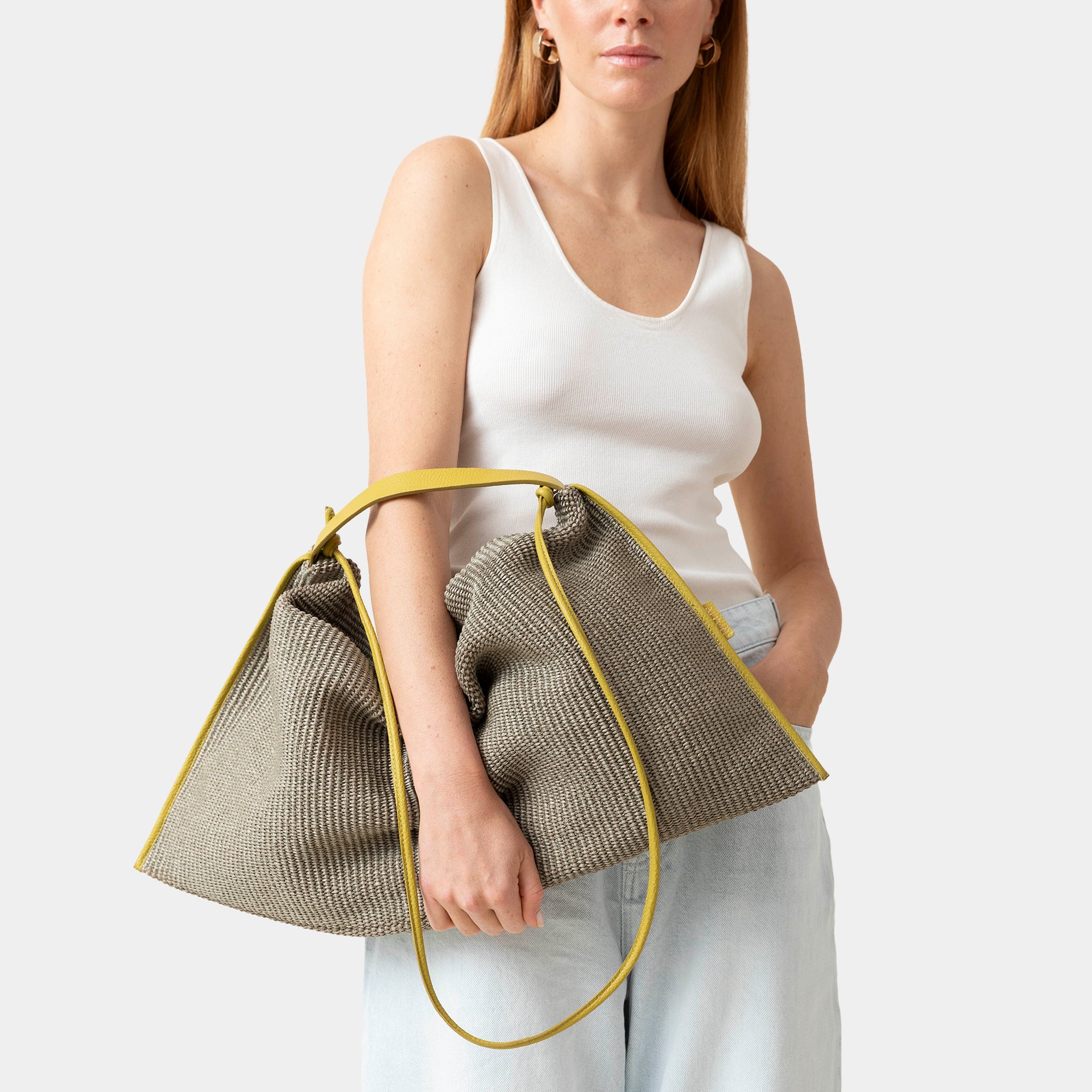 borsa Futura in rafia color muschio e profili in pelle mostarda destrutturata brand Arron Made in Italy indossata a mano capiente e morbida