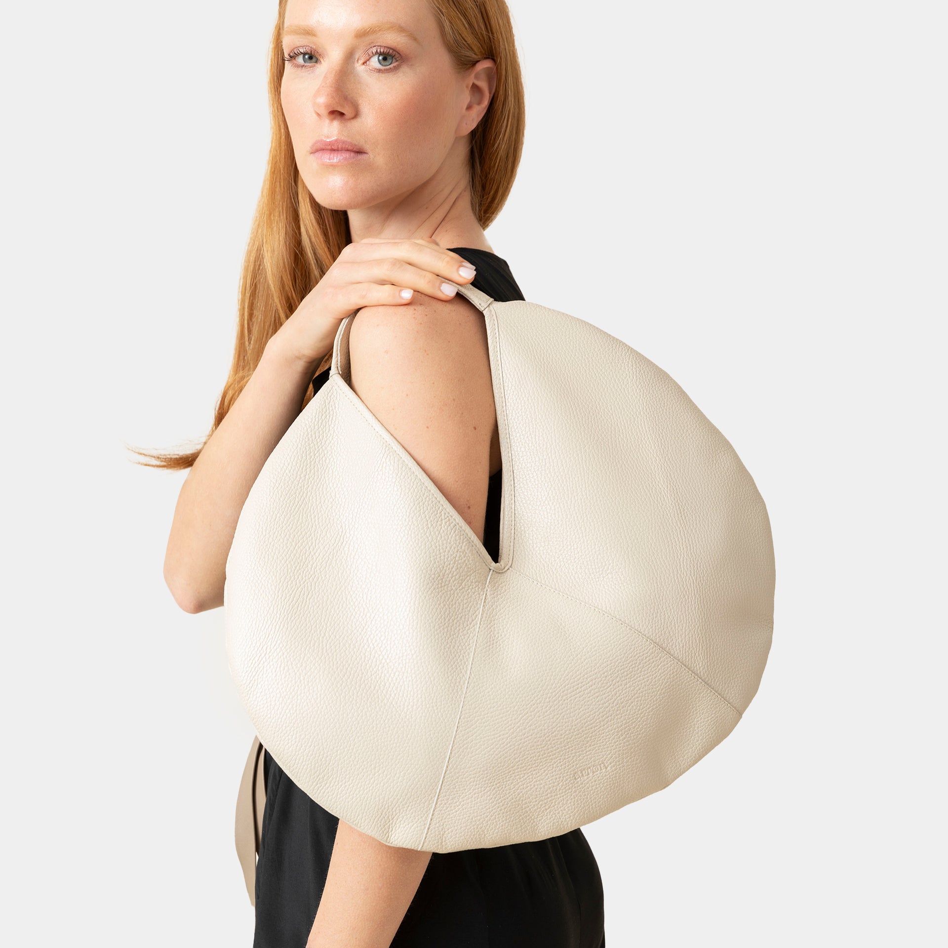 borsa rotonda NOA del brand ARRON in pelle martellata latte avena