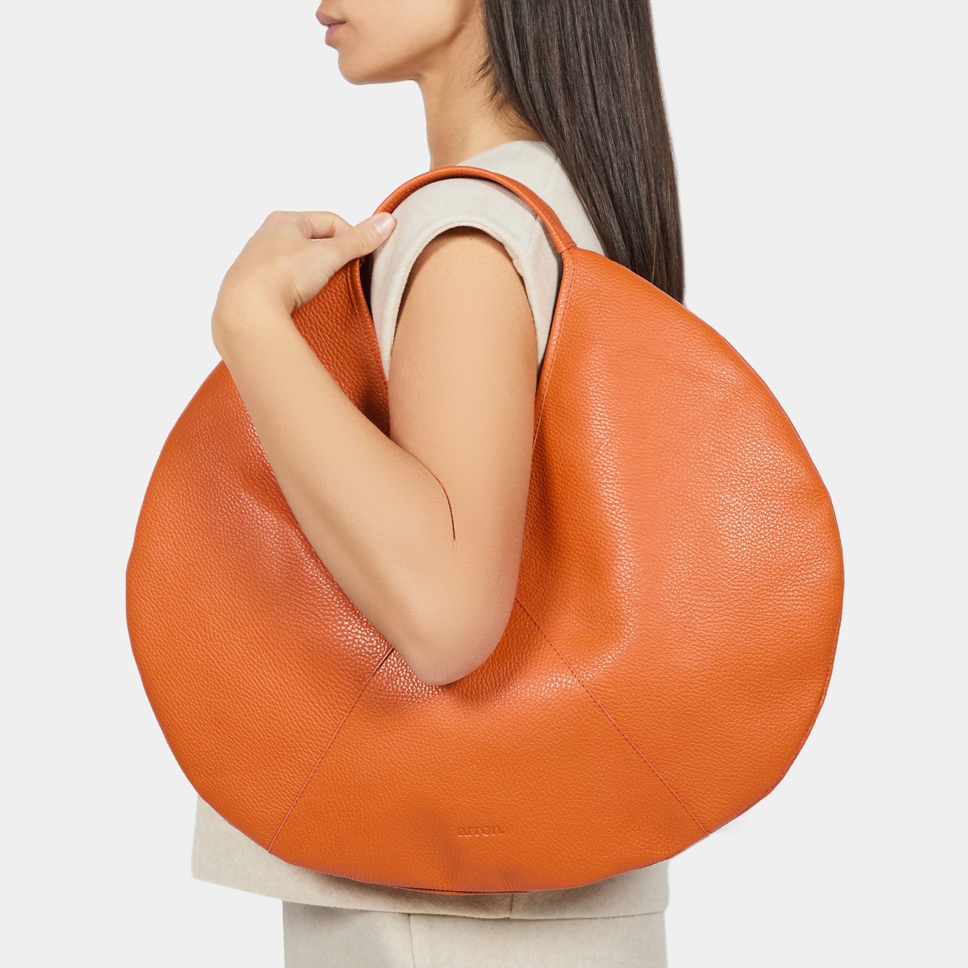 borsa rotonda NOA del brand ARRON in pelle martellata arancione carota
