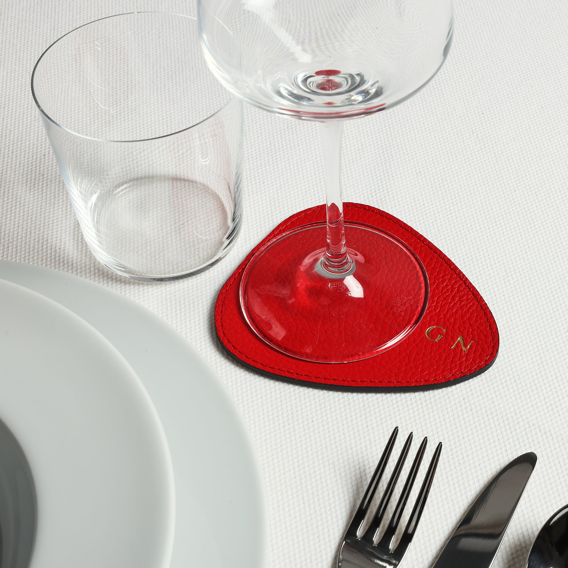 tavola delle feste con sottobicchiere e droppy personalizzato con iniziali timbro oro in pelle rossa Arron Made in Italy idea regalo natale tavola capodanno