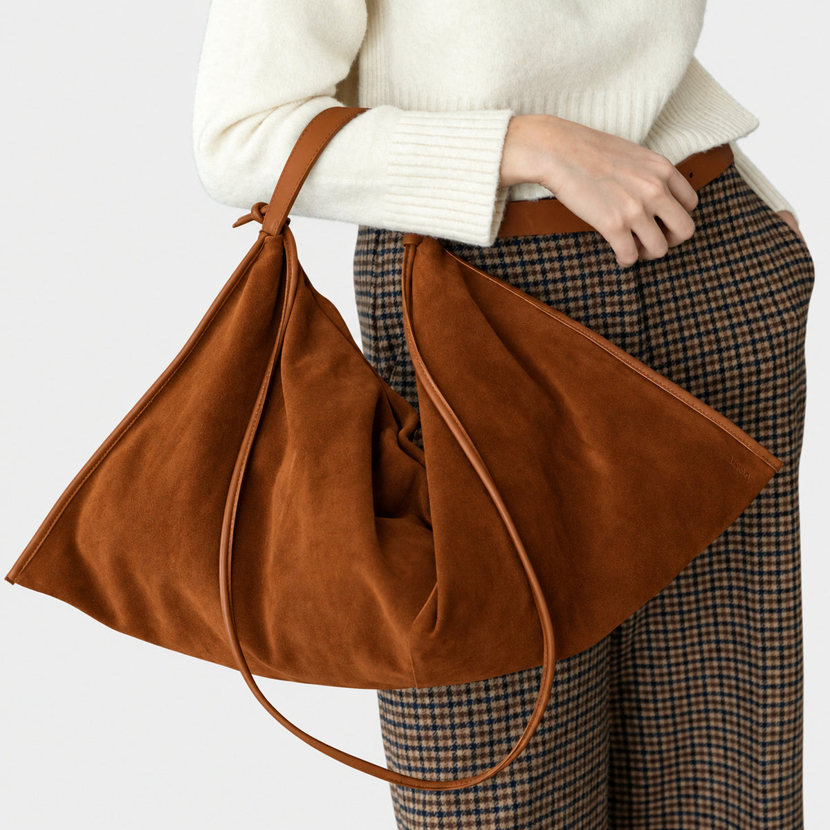 borsa destrutturata a tracolla e a spalla in camoscio cognac cammello design contemporaneo minimalista Arron Made in Italy indossata a mano
