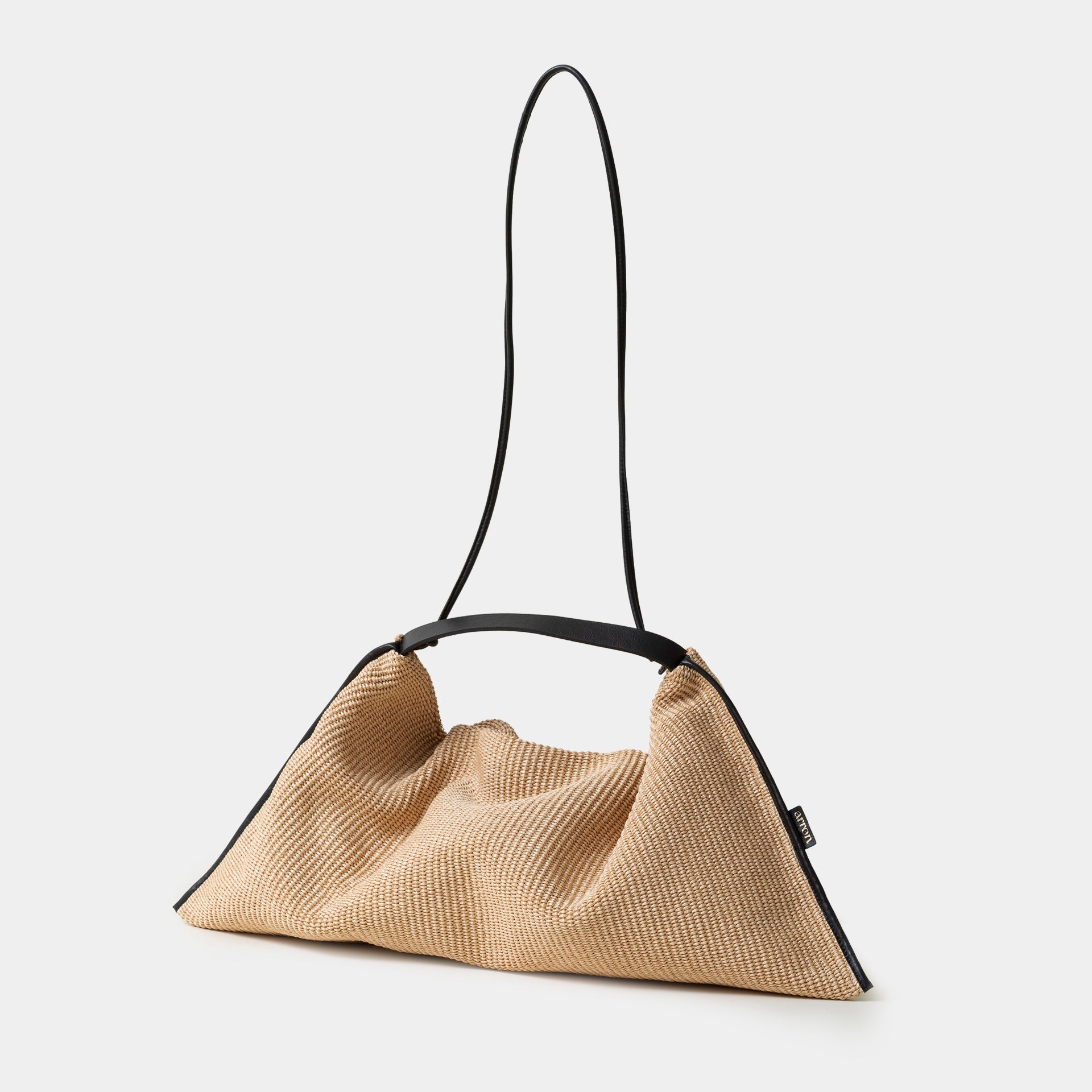 borsa Futura del brand Arron in rafia ecrù con bordi in pelle nera destrutturata con tracolla vista laterale