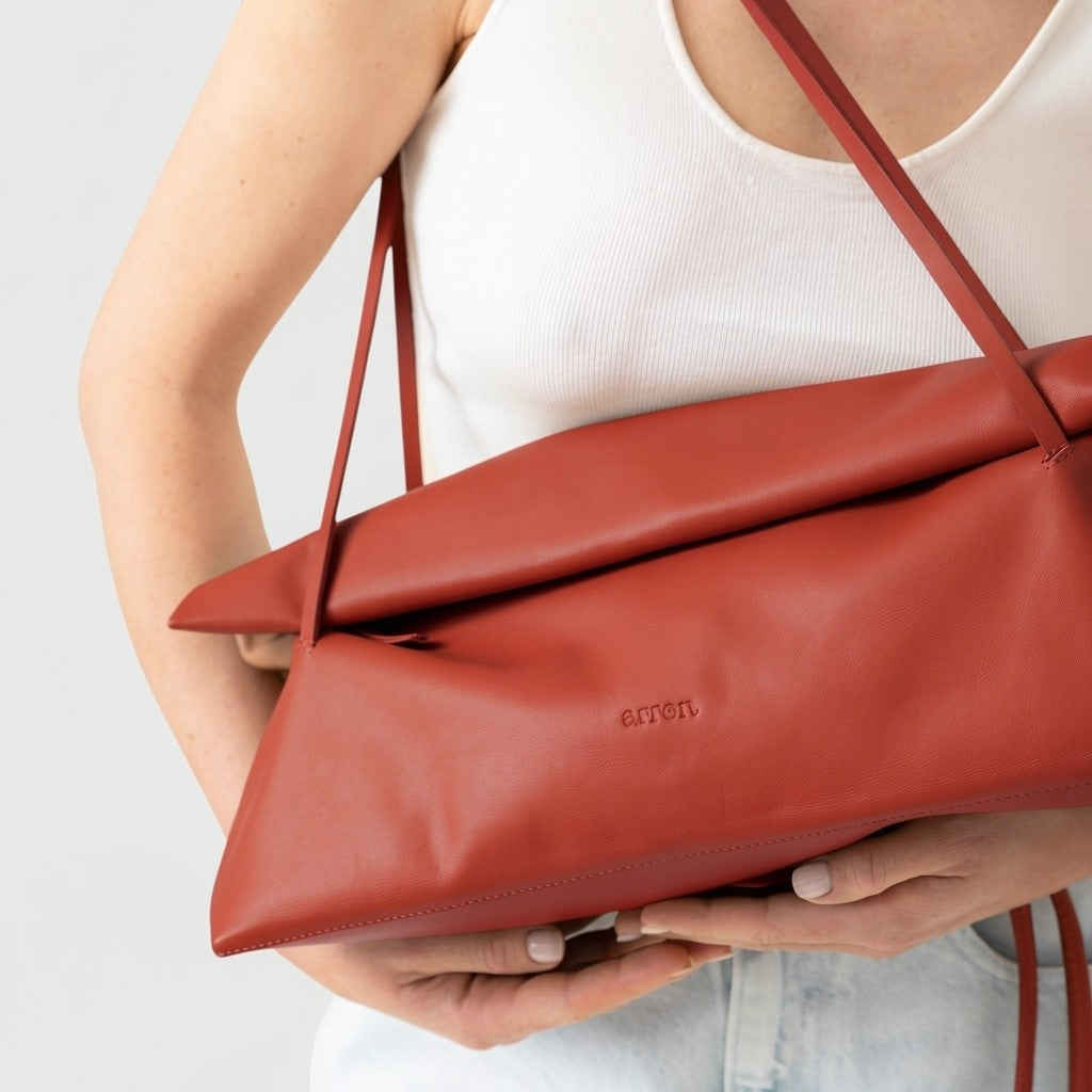 borsa Otta made in Italy del brand Arron  in pelle color mattone, forma allungata east west, trendy, leggera manici fini, indossata